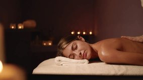 A Young and Beautiful Woman Gets a Relaxing Massage in a Spa. The Environment Is Surrounded by Candles that Create Atmosphere and Help to Relax. Concept of Women's Day, Spa Treatment. Relax. - Powered by Shutterstock - Get 15% off with code: PIKWIZARD15