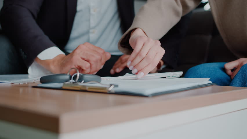 Woman hand signs car purchase agreement with mature manager in dealership closeup. Salesman makes deal with female customer buying auto in official salon