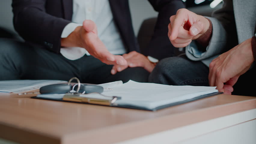 Man hand signs car purchase contract with manager consultation in dealership closeup. Male customer buys auto and insurance policy in official salon