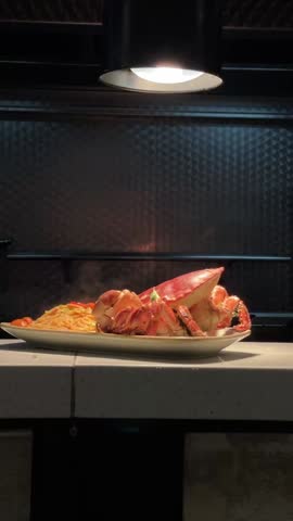 Freshly cooked crab and pasta releasing steam, served on a plate in a restaurant kitchen