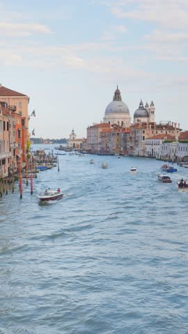 Grand Canal and Basilica Santa Maria della Salute in Venice, Italy. Boats floating along the canal. Beautifil cityscape at sunset. Famous tourist destination. Vertical video

