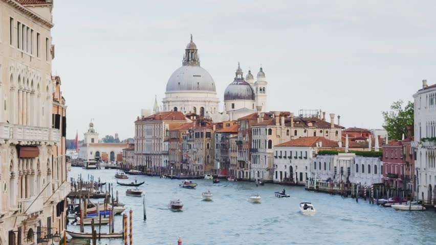 Grand Canal and Basilica Santa Maria della Salute in Venice, Italy. Boats floating along the canal. Beautifil cityscape at sunset. Famous tourist destination.
