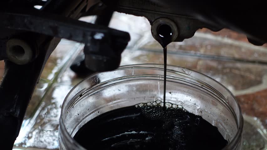 The process of draining motorcycle engine oil for refilling