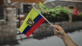 Man's hand holding ecuador flag in outdoor street setting with blurred background, showcasing national pride and diversity. - Powered by Shutterstock - Get 15% off with code: PIKWIZARD15
