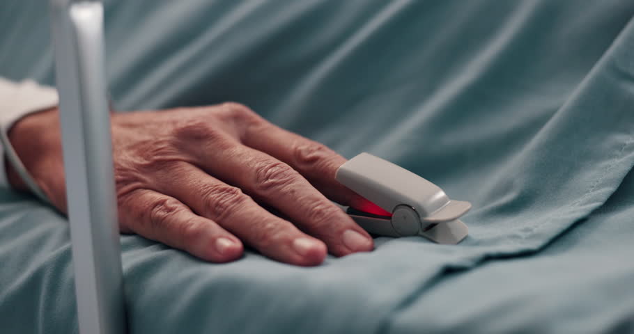 Hand, healthcare and oximeter with person in hospital bed for monitoring, recovery or treatment. Finger, heart rate and rest with patient in clinic for medical operation, procedure or surgery closeup