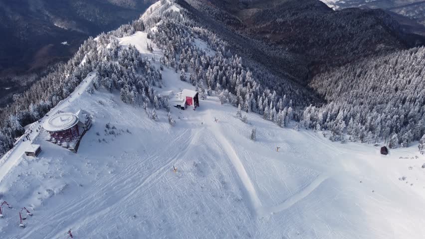 13-second 4K aerial footage flying over the snow-covered Postavarul Massif in Poiana Brasov, Romania, on a bright winter day