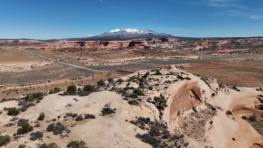 Push in Shot of Snow Capped Mountains, Orange Desert in the Foreground, Blue Skies, Moab Utah, US Highway 191, La Sal Mountains