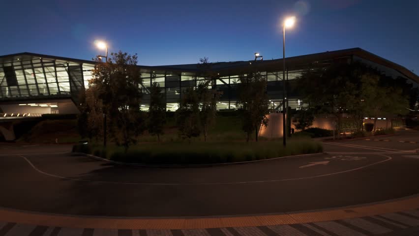Gimbal wide panning shot of a shuttle stop at the Endeavor Building on the Nvidia campus at twilight in Silicon Valley, California. 4K