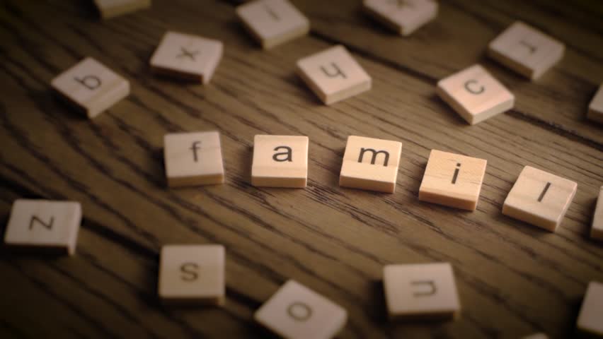 Wooden tiles spell the word family as the camera gently pans across a rustic wooden surface in warm lighting.