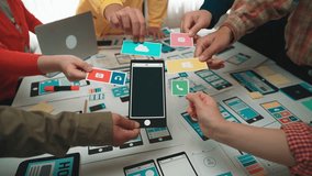 A diverse team collaborates on designing a mobile app interface, illustrating vibrant screens on various devices in a creative workspace. They brainstorm innovative ideas together. SACTR - Powered by Shutterstock - Get 15% off with code: PIKWIZARD15