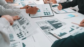 A group of professionals collaborates during a meeting, analyzing various business charts and graphs laid out on the table, highlighting critical data insights. SACTR - Powered by Shutterstock - Get 15% off with code: PIKWIZARD15