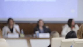 Group of people are sitting in a conference room, with a large screen behind them. The people are looking at the screen, which is displaying a presentation. Scene is professional and focused - Powered by Shutterstock - Get 15% off with code: PIKWIZARD15