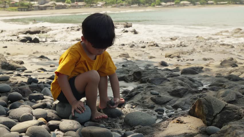 A young boy is playing with sand on the beach
