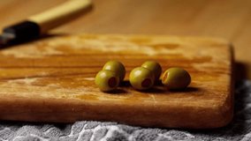 person is picking up a pickle olive stuffed with red pimento pepper from the wooden cutting board by poking it with a fork - Powered by Shutterstock - Get 15% off with code: PIKWIZARD15