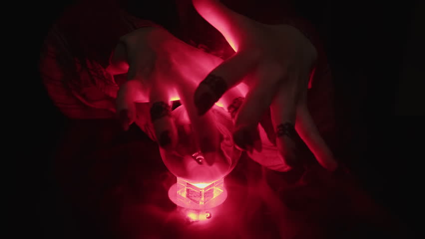 Female hands of  fortuneteller witch over magical crystal ball making witchcraft movements close-up.