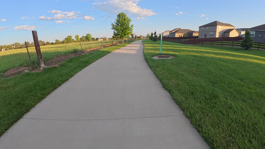 First person POV from bike riding in springtime scenery on the Poudre River Trail, approaching the trail end in Timnath, Colorado