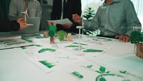 A diverse team collaborates on a sustainability project, presenting eco-friendly concepts and prototypes with green elements displayed on the table. SACTR - Powered by Shutterstock - Get 15% off with code: PIKWIZARD15