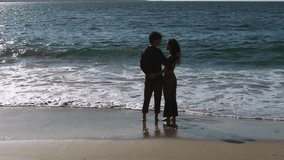 Young Couple Embracing While Standing On Sandy Beach With Waves Splashing. Muxia, Spain. orbiting shot - Powered by Shutterstock - Get 15% off with code: PIKWIZARD15