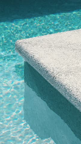 Clear blue water in the pool. Steps into the pool. The edge of the pool is finished with a gray curbstone. Relaxation in the backyard of a country house
