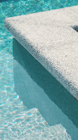 Clear blue water in the pool. Steps into the pool. The edge of the pool is finished with a gray curbstone. Relaxation in the backyard of a country house
