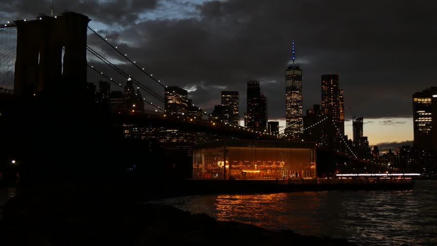 Brooklyn Bridge, New York City Manhattan downtown skyline cityscape, United States. Waterfront Pebble Beach, carousel in Dumbo, USA. Dramatic twilight dusk. Evening or night sky. World Trade Center.