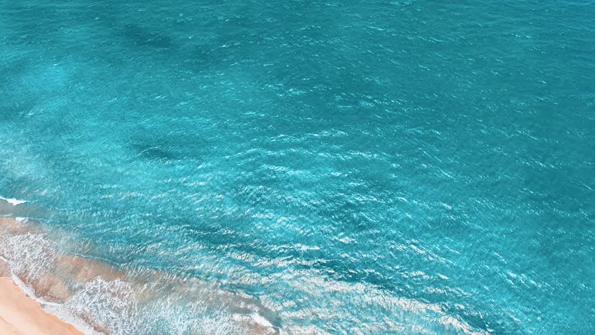 Empty tropical beach and seascape. Ocean and coast. Soft blue ocean wave on sandy tropical beach. Cruise. Sea wave with foam rolling onto the shore. Summer vacation in the tropics. Copy space.