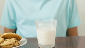 A person is sitting at a table with a glass of milk and a plate of cookies - Powered by Shutterstock - Get 15% off with code: PIKWIZARD15