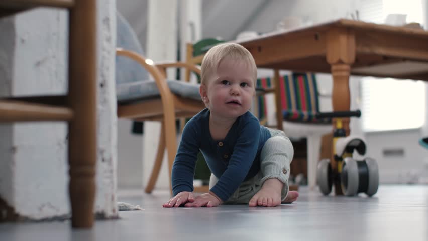 Joyful baby crawls excitedly across the warm, inviting floor, looks at camera, eagerly discovering vibrant surroundings in a loving, happy home filled with comfort and delightful experiences