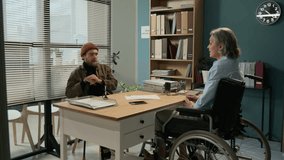 Social worker in wheelchair consulting man about medical insurance while new African American client entering office - Powered by Shutterstock - Get 15% off with code: PIKWIZARD15