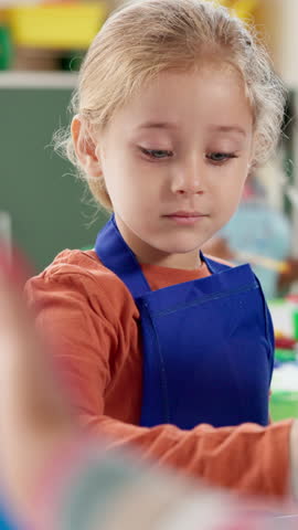 Girl, child and painting on artwork in classroom for creative lesson, art project and motor skills development. Kindergarten, kid student and paintbrush for color activity, education and coordination