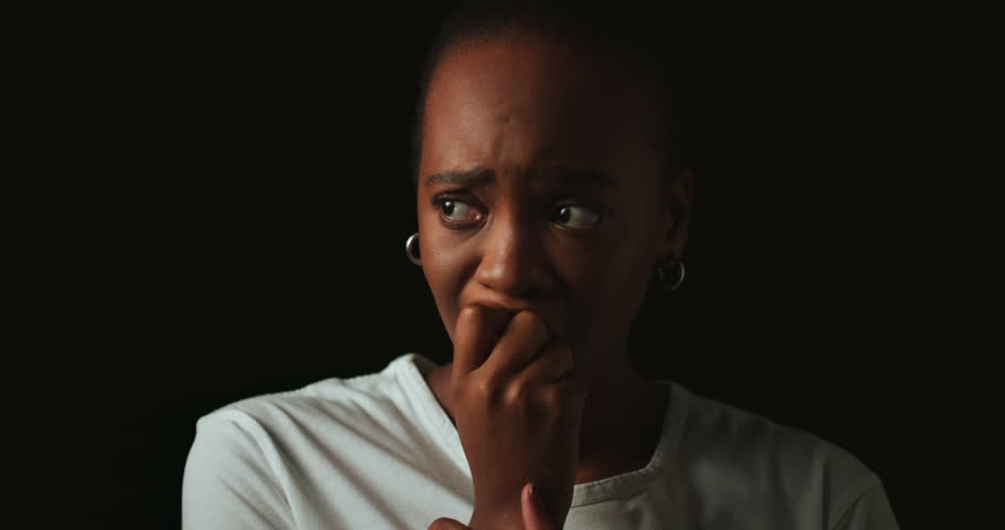 Stress, worry and face of black woman on dark background with fear, nervous and confused expression. Scared, anxiety and isolated female person with phobia, emotions and crisis reaction in studio