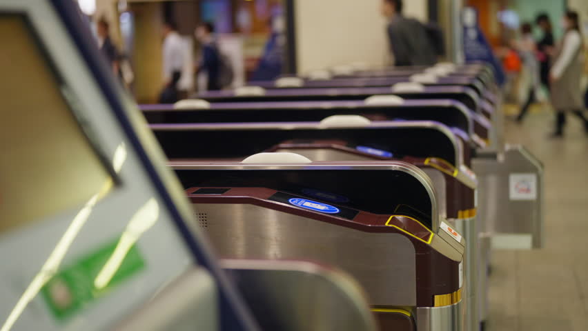 Crowd of People walking pass ticket gate in subway station in rush hour morning. Passenger using card and smartphone mobile app making payment for public transportation at train station in the city.
