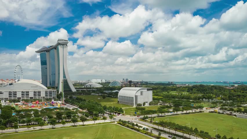 Aerial panoramic timelapse of Marina Bay in Singapore on a sunny day, showcasing the iconic city skyline, Marina Bay Sands hotel, lush gardens, and modern urban architecture.