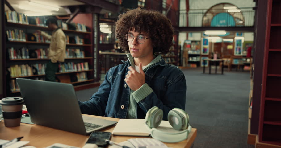Laptop, thinking and man student with notebook in library studying for university exam with textbooks. Education, computer and male person writing ideas with learning for college test on campus.