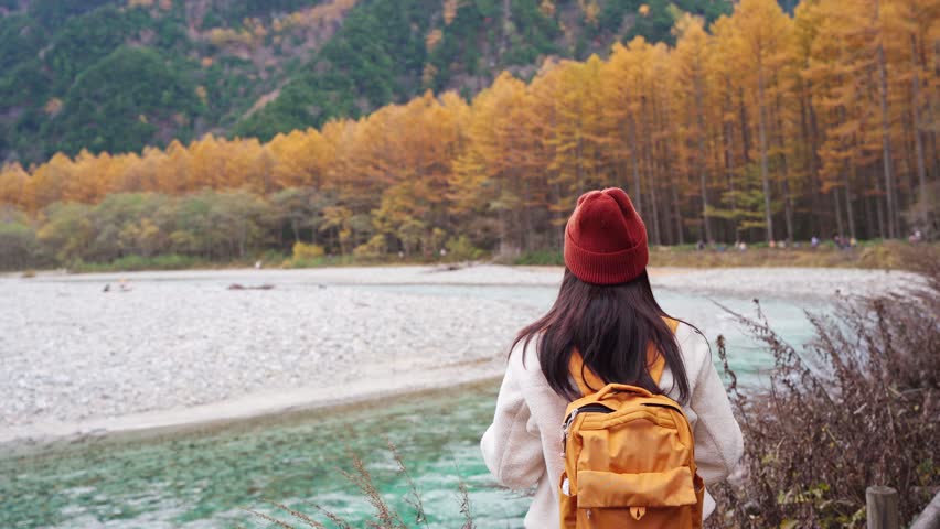 Young female tourist enjoying and taking a photo with beautiful autumn at kamikochi in Japan