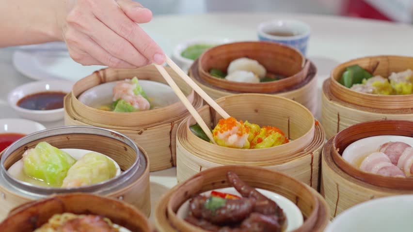Young woman traveler eating traditional Chinese Dim Sum at restaurant