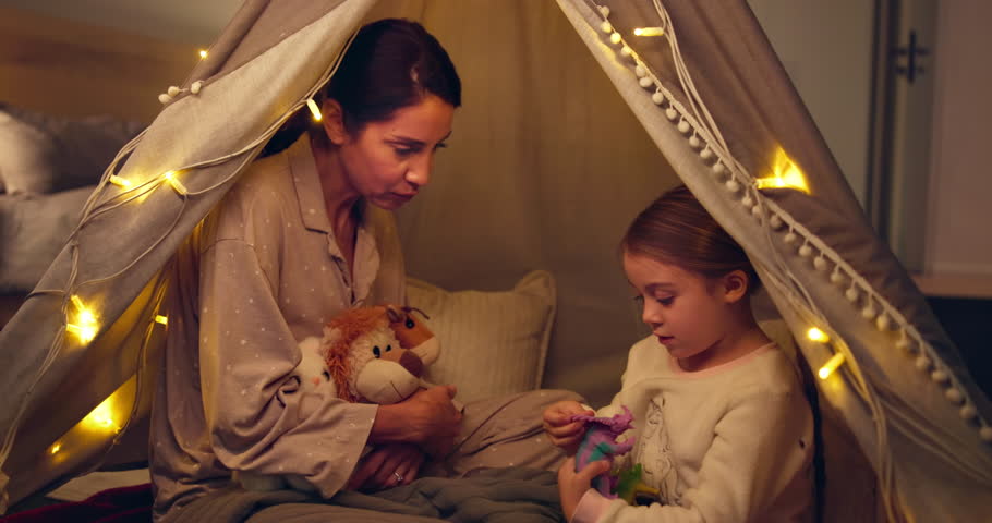 Tent, mother and child play with toy dinosaur, miniature model and bonding together in family home. Mom, parent and daughter with stuffed animal for game, learning or explain reptile species at night