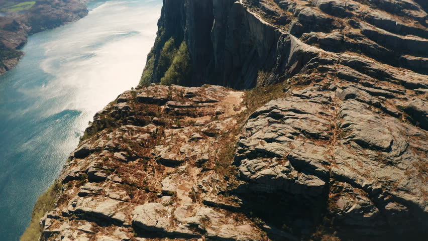 Iconic Preikestolen dramatically meets still waters of Lysefjord. Immense scale of rock formation and picturesque panorama of Norway aerial view