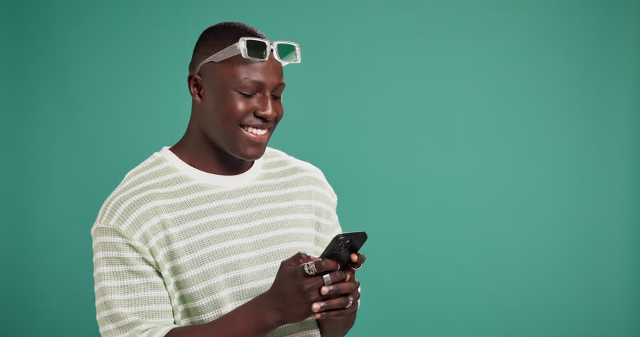 Dating app, phone and reaction with black man on green background for search for social media match. Mobile, smile and swipe with happy African person in studio space for profile browsing on internet