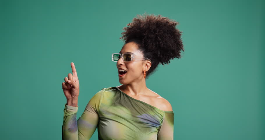 Woman, point up and sunglasses in studio, space and options with trendy style by background. Person, girl and excited with decision for mockup, fashion and announcement with pride in Costa Rica