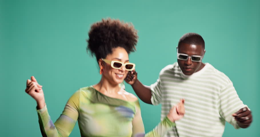 African couple, happy and dancing in studio with sunglasses, fashion and excited by background. People, man and woman with movement, rhythm and partner with smile for trendy style with celebration