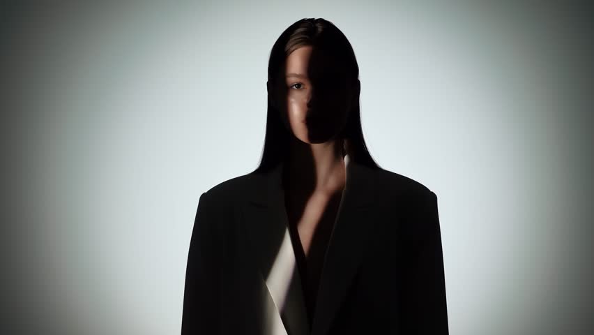 A striking portrait capturing a woman in dramatic lighting, with one side of her face in shadow, creating a mysterious effect.