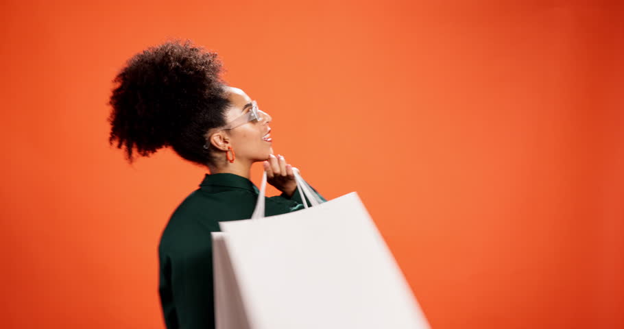 Shopping bag, sunglasses and woman in studio happy for bargain, retail sale and discount. Space, fashion and portrait of person with smile for products, cosmetics and style on orange background