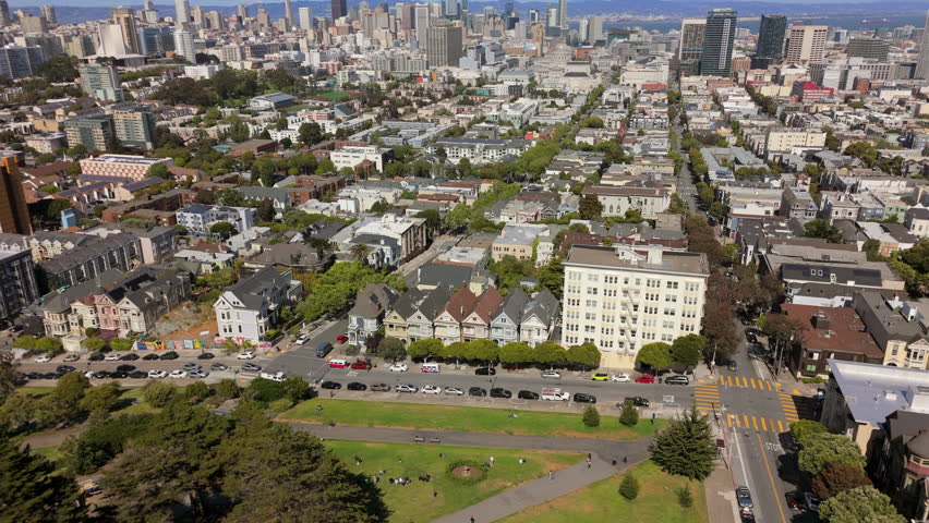 Stunning aerial footage captures a vibrant urban neighborhood Painted Ladies of San Francisco, highlighting beautiful city skyline, lush green parks, and a blend of residential areas