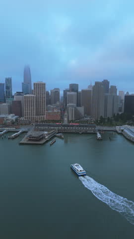 Breathtaking aerial drone shot captures the stunning views over San Francisco Bay, showcasing the iconic skyline, bustling pier activities, and a light morning fog enveloping the city