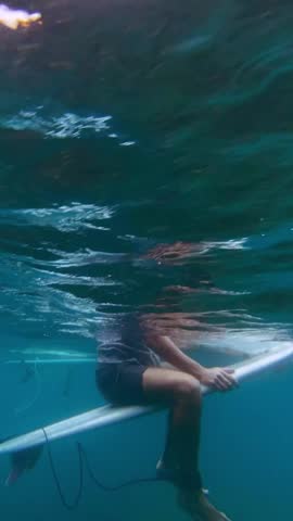Underwater view of two surfers in Indian Ocean waiting waves. Vertical video