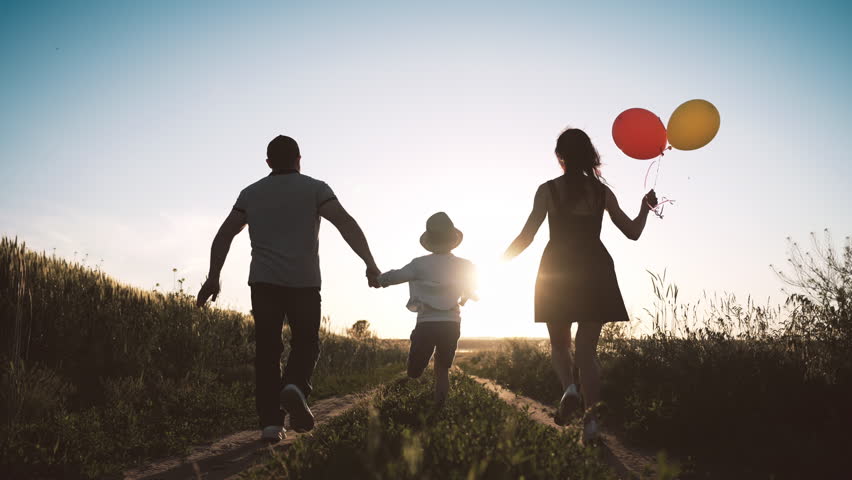 Joyful little boy holding hands of parents and running on field, rear view. Happy childhood moments, slow motion with people enjoying simple life, carefree child with mother and father in summer