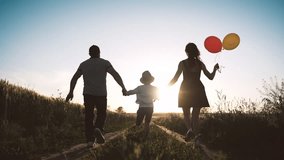 Joyful little boy holding hands of parents and running on field, rear view. Happy childhood moments, slow motion with people enjoying simple life, carefree child with mother and father in summer - Powered by Shutterstock - Get 15% off with code: PIKWIZARD15