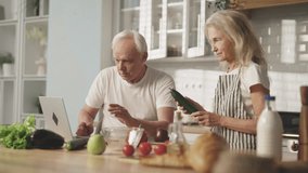 Elderly people cooking at home, old man and woman looking for video recipe. Elderly man surfing internet with cook web-sites and mature wife cooking vegetable salad, healthy nutrition and organic food - Powered by Shutterstock - Get 15% off with code: PIKWIZARD15