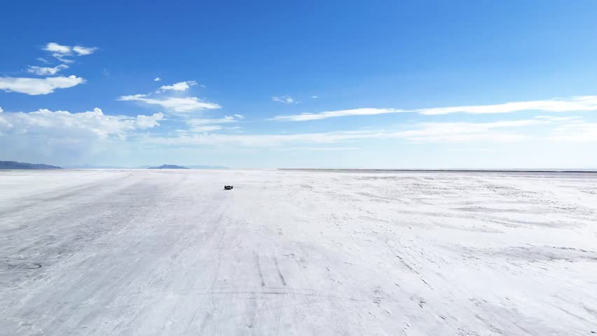 Aerial drone tilt up shot showing wide white salt flat stretching to horizon with vivid blue sky and distant mountains in remote West Virginia, highlighting contrast of terrain and open landscape